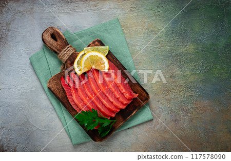 chum salmon, cold smoked, sliced, on a cutting board, with lemon and parsley, top view, close-up, no people, 117578090