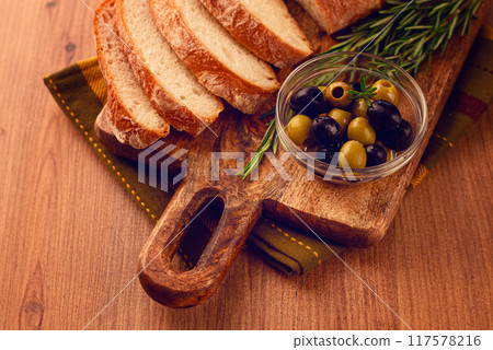 sliced ciabatta , on a chopping board, with rosemary and olives, Italian bread, close-up, Italian cuisine, breakfast, no people, 117578216