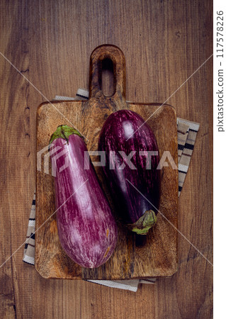 purple and white eggplant, on a wooden chopping board, top view, raw eggplant, no people, 117578226