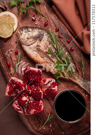Fried dorado fish, with spices and herbs, on a wooden board, pomegranate sauce, close-up, no people, Fried dorado fish, with spices and herbs, on a wooden board, pomegranate sauce, close-up, no people, 117578312