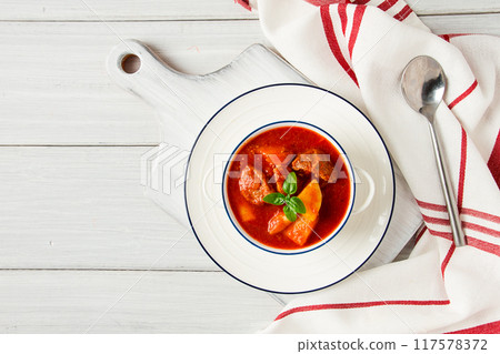 Potatoes stewed with meat, in tomato sauce, with spices and herbs, no people, on a white table, 117578372