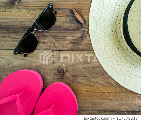 Summer vacation, flatlay. Hat, flip flops and swimsuit on a dark wooden background. Summer vacation, flatlay. Hat, flip flops and swimsuit on a dark wooden background. 117579238
