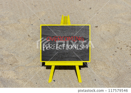 Overcoming perfectionism symbol. Concept words Overcoming perfectionism on beautiful yellow blackboard. Beautiful sand beach background. Business Overcoming perfectionism concept. Copy space. 117579546