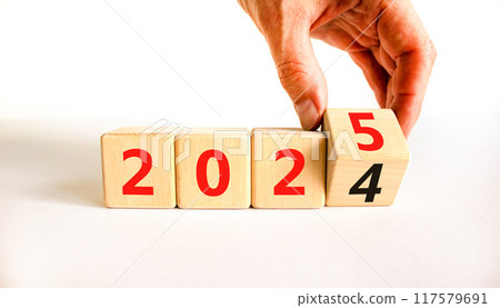 Business concept of 2025 new year symbol. Businessman turns wooden cube and changes number 2024 to 2025. Beautiful white table white background, copy space. Business 2025 happy new year concept. Business concept of 2025 new year symbol. Businessman turns wooden cube and changes number 2024 to 2025. Beautiful white table white background, copy space. Business 2025 happy new year concept. 117579691