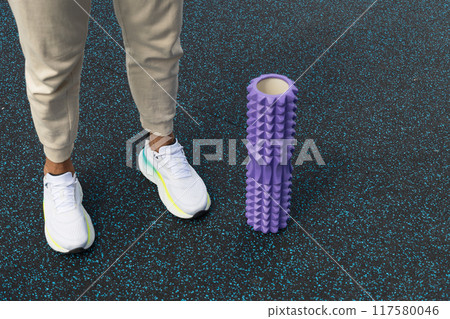 Man preparation to stretching with massage roll at sports ground. Outdoors. Yoga, sport, healthy lifestyle concept. Myofascial Release. Close up. Copy space. 117580046