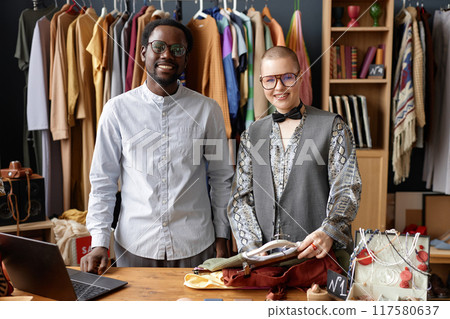 Medium portrait shot of two happy second hand shop assistants in vintage glasses smiling while looking at camera at thrift shop checkout Medium portrait shot of two happy second hand shop assistants in vintage glasses smiling while looking at camera at thrift shop checkout 117580637