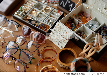 Close up on vintage sunglasses, unique rings and earrings displayed on table at thrift store Close up on vintage sunglasses, unique rings and earrings displayed on table at thrift store 117580754