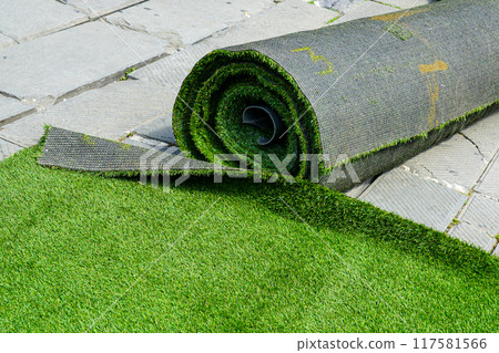 Preparing artificial grass carpet rolls for outdoor event flooring in the town square 117581566