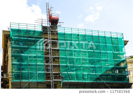 House facade renovation using prefabricated metal tube scaffolding covered with green safety net 117581568