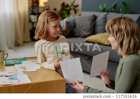 Young mom holding cards with animals and letters while learning alphabet with her girl Young mom holding cards with animals and letters while learning alphabet with her girl 117581616