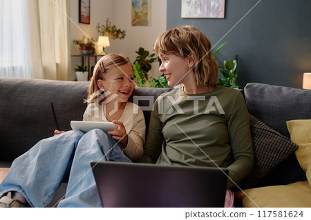 Young mom working remotely and smiling to her happy child 117581624