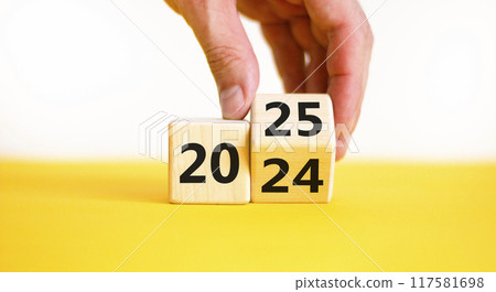 Business concept of 2025 new year symbol. Businessman turns wooden cube and changes number 2024 to 2025. Beautiful yellow table white background, copy space. Business 2025 happy new year concept. 117581698