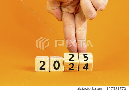 Business concept of 2025 new year symbol. Businessman turns wooden cube and changes number 2024 to 2025. Beautiful orange table orange background, copy space. Business 2025 happy new year concept. Business concept of 2025 new year symbol. Businessman turns wooden cube and changes number 2024 to 2025. Beautiful orange table orange background, copy space. Business 2025 happy new year concept. 117581770