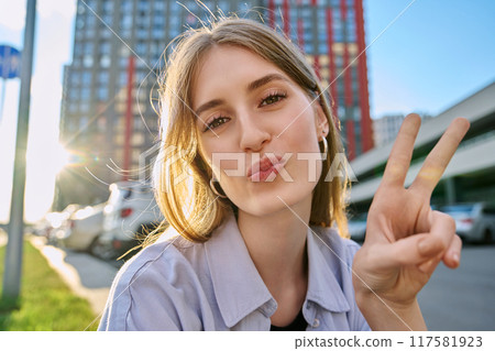 Selfie portrait of young happy blonde female looking at camera outdoor 117581923