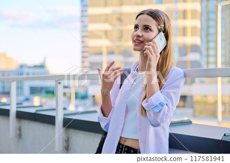 Beautiful young teenage female talking on mobile phone, modern city background 117581941