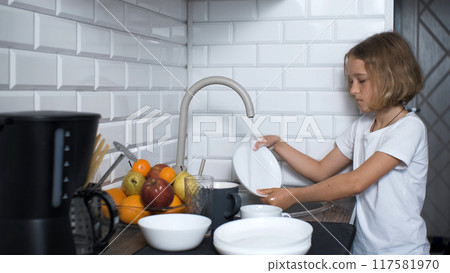 Young girl washing dishes in the kitchen sink, dressed in a white t-shirt, household duties Young girl washing dishes in the kitchen sink, dressed in a white t-shirt, household duties 117581970