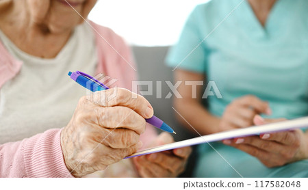 Elderly Woman Signing Documents At Nursing Home Elderly Woman Signing Documents At Nursing Home 117582048