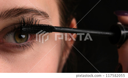Girl Applying Black Mascara To Her Long Eyelashes Girl Applying Black Mascara To Her Long Eyelashes 117582055