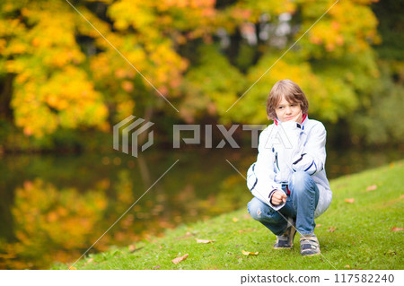 Child in fall park. Kid with autumn leaves. 117582240