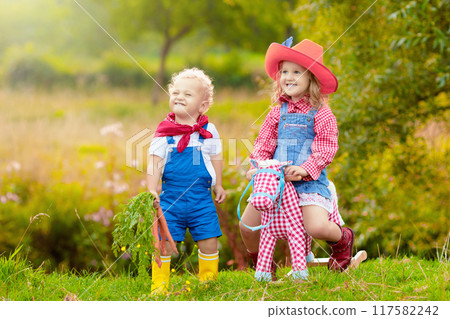 Cowboy kids playing with toy horse Cowboy kids playing with toy horse 117582242