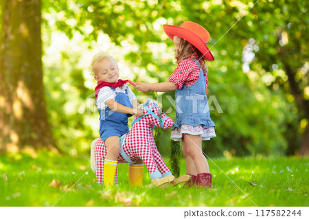 Cowboy kids playing with toy horse Cowboy kids playing with toy horse 117582244
