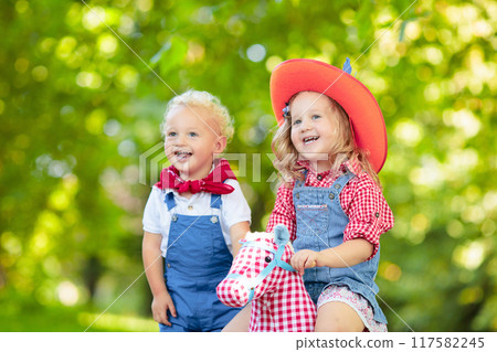 Cowboy kids playing with toy horse Cowboy kids playing with toy horse 117582245