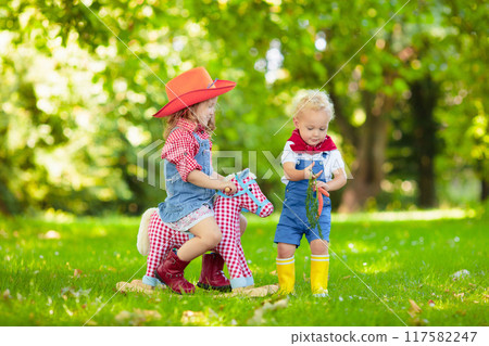 Cowboy kids playing with toy horse Cowboy kids playing with toy horse 117582247