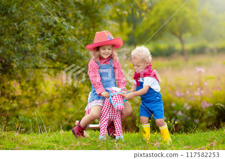 Cowboy kids playing with toy horse Cowboy kids playing with toy horse 117582253