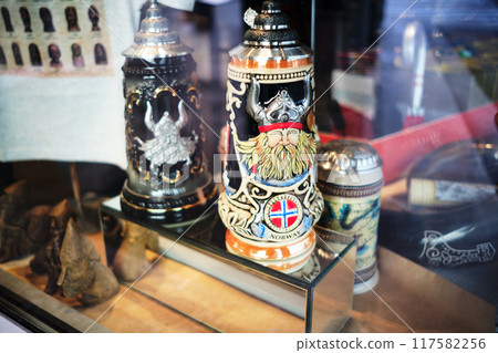 Bergen, Norway - July 24, 2023: Souvenir vessel with the image of a blond Viking in a horned helmet and the Norwegian flag Bergen, Norway - July 24, 2023: Souvenir vessel with the image of a blond Viking in a horned helmet and the Norwegian flag 117582256