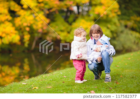 Child in fall park. Kid with autumn leaves. 117582377
