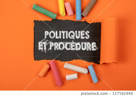 POLICIES AND PROCEDURE in French. Text under torn orange paper on a blackboard POLICIES AND PROCEDURE in French. Text under torn orange paper on a blackboard 117582948