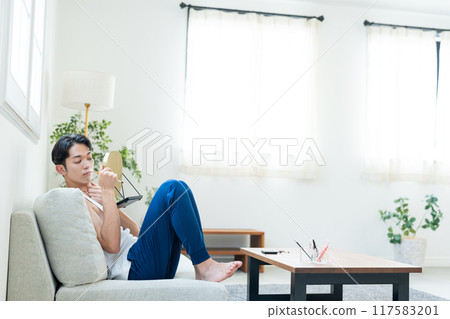 Young man putting on make-up in the living room Young man putting on make-up in the living room 117583201