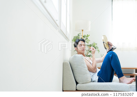 Young man putting on make-up in the living room Young man putting on make-up in the living room 117583207