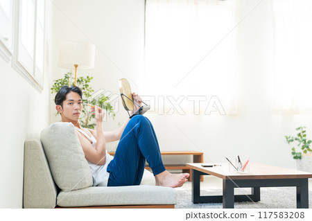 Young man putting on make-up in the living room Young man putting on make-up in the living room 117583208