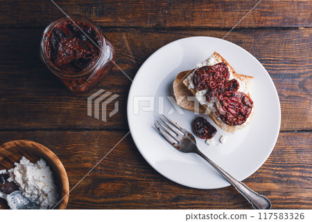Toasts with cream cheese and sundried tomatoes on a white plate 117583326