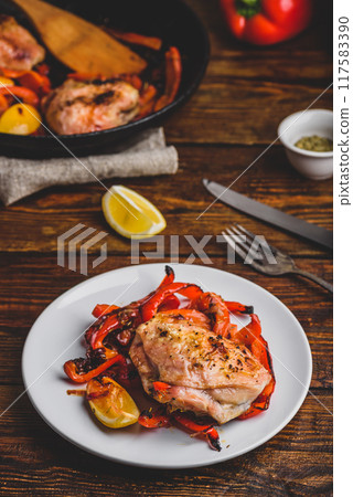 Baked chicken thighs with red bell peppers and lemon 117583390