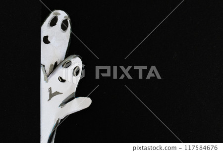 Pair of ghosts peeping out from behind a wall, paper cutout on dark background. Pair of ghosts peeping out from behind a wall, paper cutout on dark background. 117584676