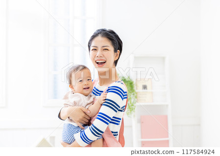 Nursery teacher holding a baby Nursery teacher holding a baby 117584924