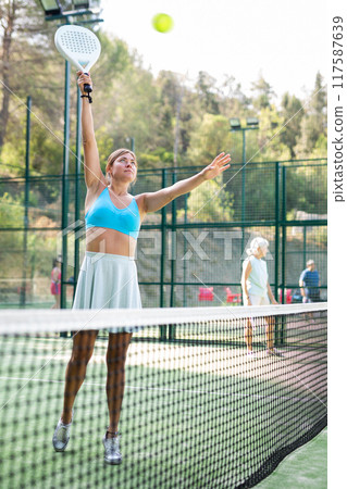 Sporty young woman playing padel on open court on summer Sporty young woman playing padel on open court on summer 117587639