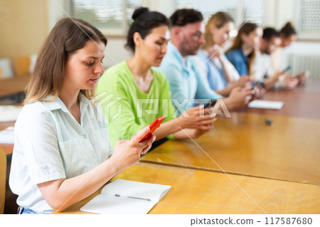 Portrait of students using mobile phones during lesson Portrait of students using mobile phones during lesson 117587680
