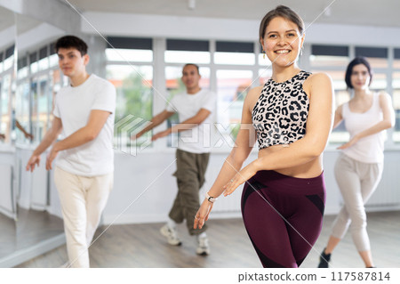 Girl enjoys active dancing, learns new movements, moves synchronously with participants of lesson 117587814