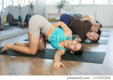 Group of people doing yoga with group in studio, performing hamstring and low back stretching Ardha Pawanmuktasana Group of people doing yoga with group in studio, performing hamstring and low back stretching Ardha Pawanmuktasana 117587838
