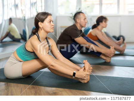 People doing yoga position while sitting on floor in modern sport club 117587877