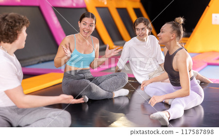 Two women and two teenager boys talking in trampoline center 117587898