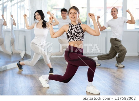 Cheerful young female instructor leading zumba class 117588008