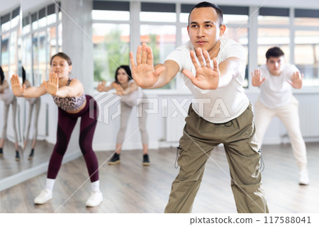 Group of women and men enjoying active dance movement in modern studio Group of women and men enjoying active dance movement in modern studio 117588041