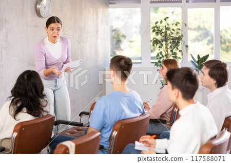 Young female professor explaining subject to group of students 117588071