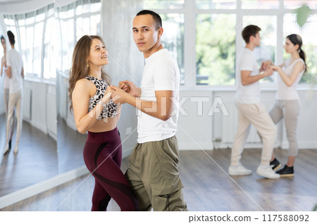 Girl paired up with young man, they train to perform slow waltz dance, rehearse performance. Girl paired up with young man, they train to perform slow waltz dance, rehearse performance. 117588092