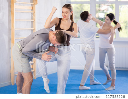 Young girl practicing self-defense techniques in pairs with middle-aged man 117588226