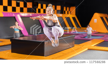Sportive European female in active wear bouncing and jumping on trampolines in leisure sports center Sportive European female in active wear bouncing and jumping on trampolines in leisure sports center 117588286